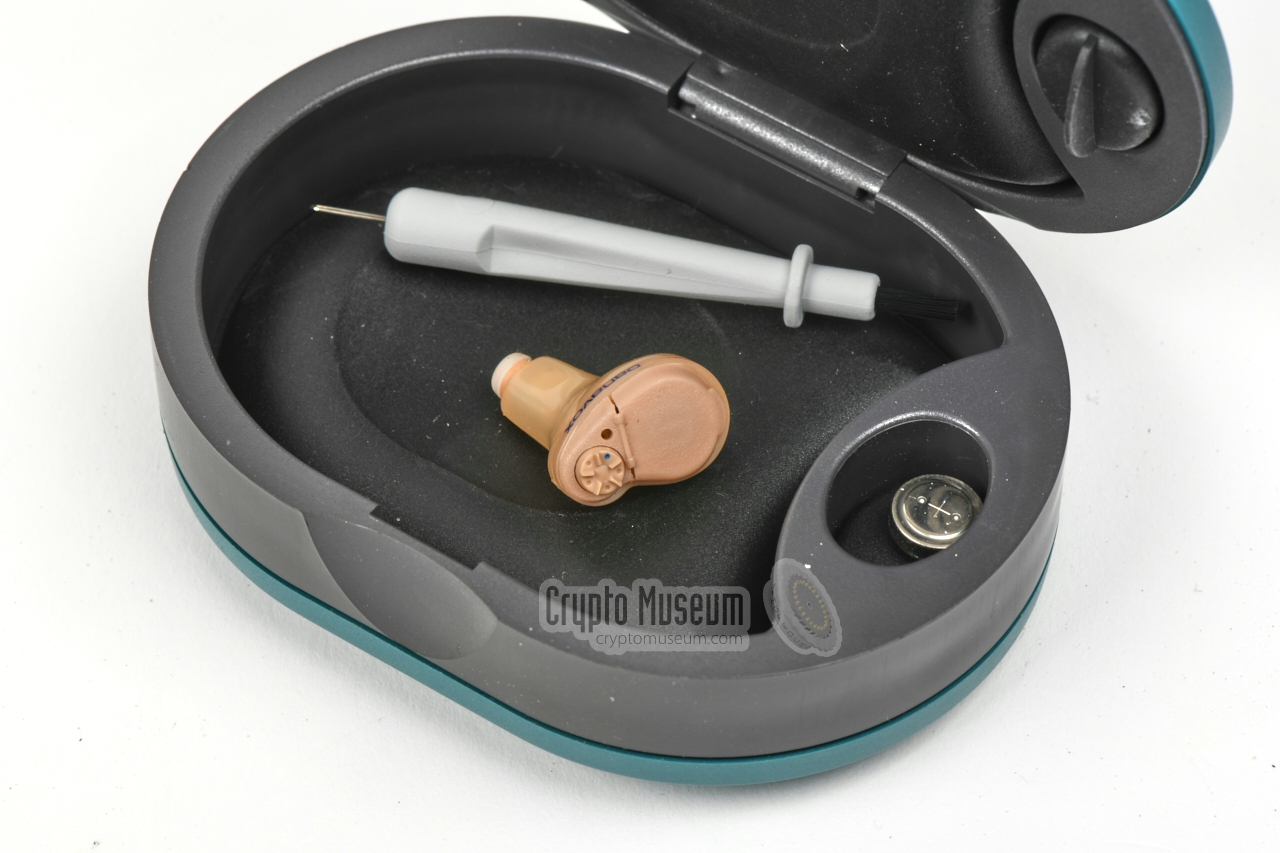 Danavox container with 131-CD/T earpiece, cleaning tool and battery