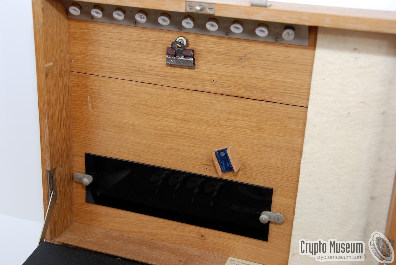 The top lid of the wooden box which is also the storage place for the spare light bulbs, the paper clip and the green lamp filter.